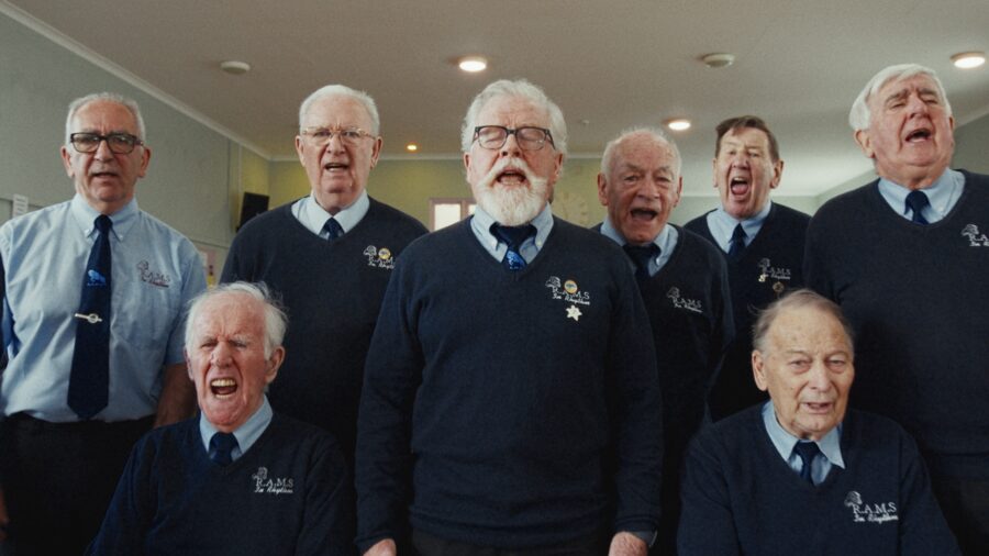 A men's choir mid-song in a community hall