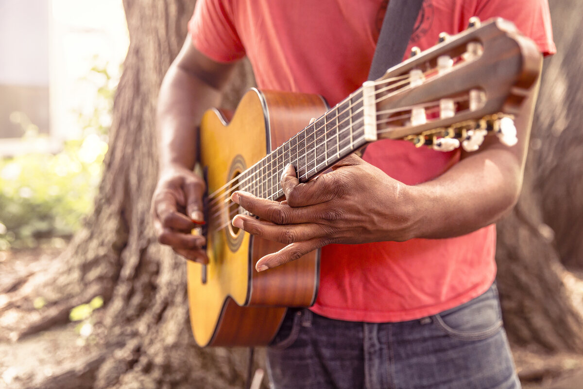 A man playing acoustic guitar outdoors
