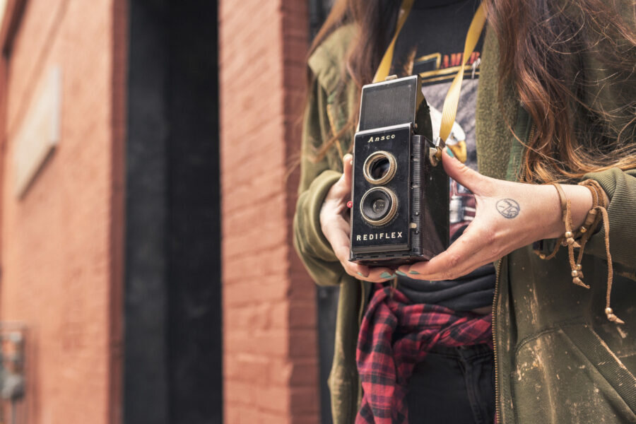 A woman holding a vintage twin-lens camera up to shoot