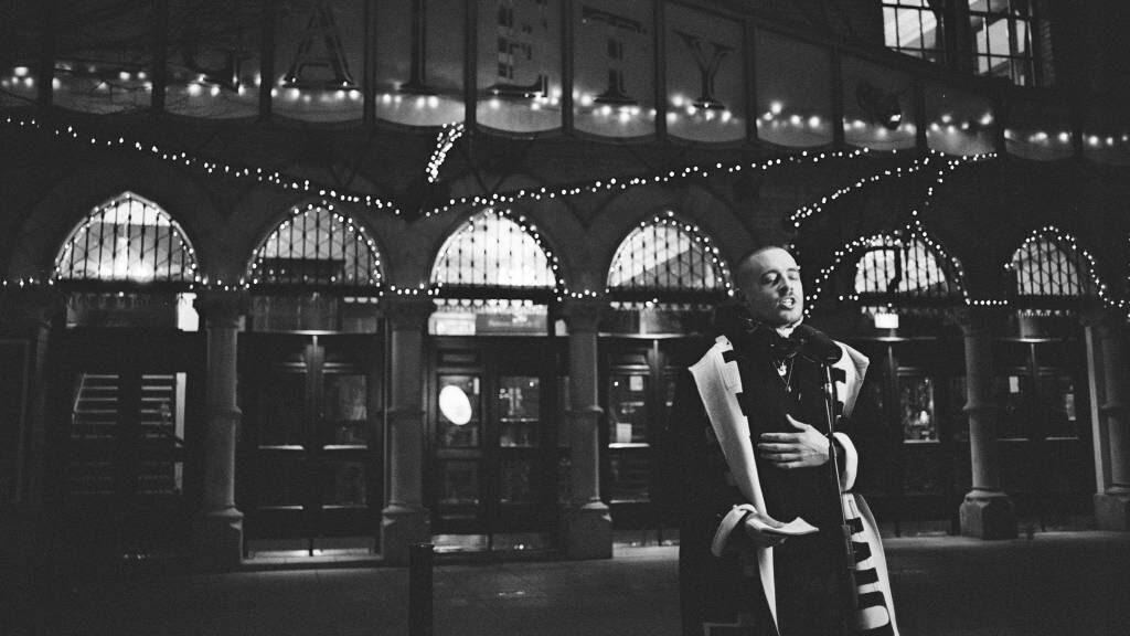 A singer performing at night under the lit arcade of the Grafton Street Powerscourt entrance, monochrome