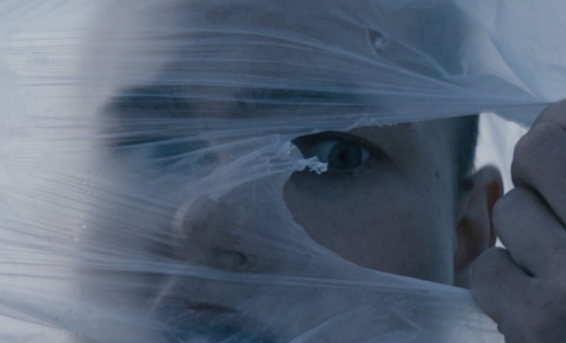 An eye seen through torn, wind-blown plastic sheeting